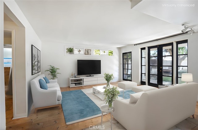 living area with light wood-type flooring, plenty of natural light, and french doors