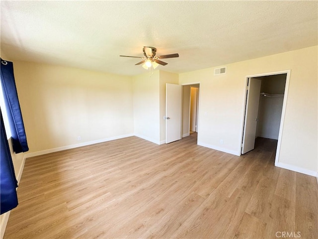 unfurnished bedroom with ceiling fan, a textured ceiling, visible vents, baseboards, and light wood-style floors