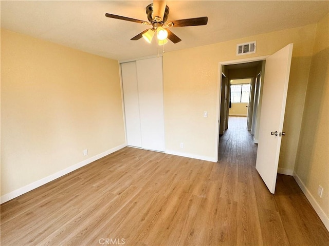 unfurnished bedroom with light wood-type flooring, a closet, visible vents, and baseboards