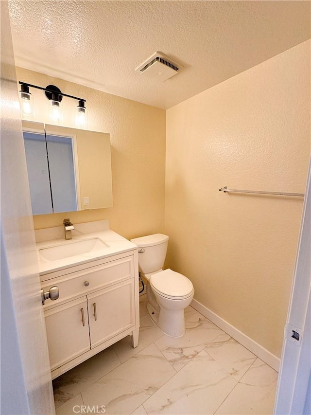 bathroom with toilet, vanity, visible vents, baseboards, and marble finish floor