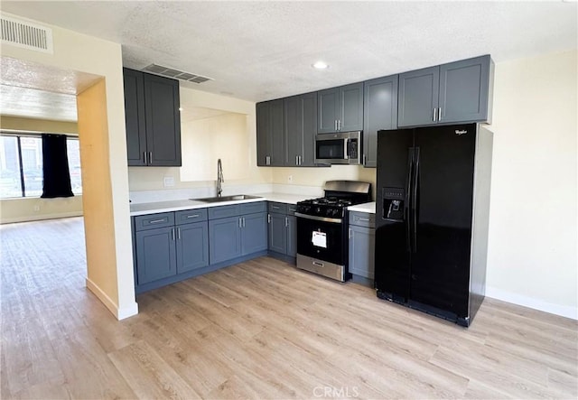 kitchen with visible vents, range with gas cooktop, stainless steel microwave, black fridge, and a sink