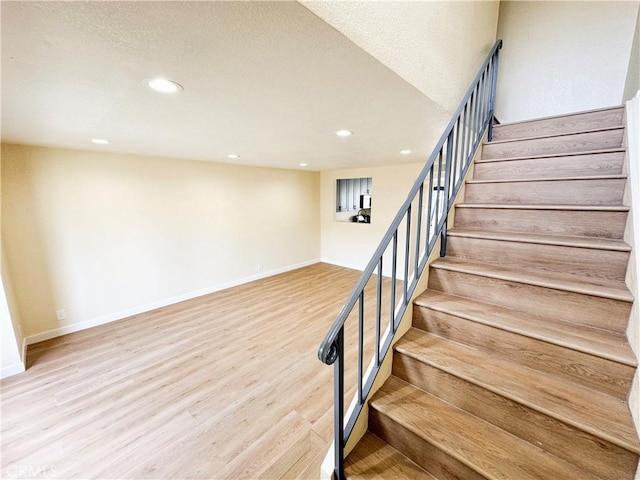 stairway featuring baseboards, wood finished floors, and recessed lighting