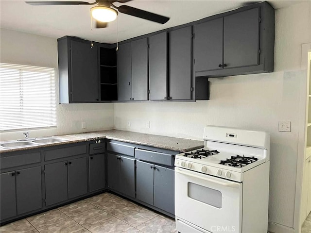 kitchen featuring open shelves, gray cabinets, a sink, and white range with gas cooktop