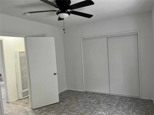 unfurnished bedroom featuring a ceiling fan, a textured ceiling, a heating unit, and a closet