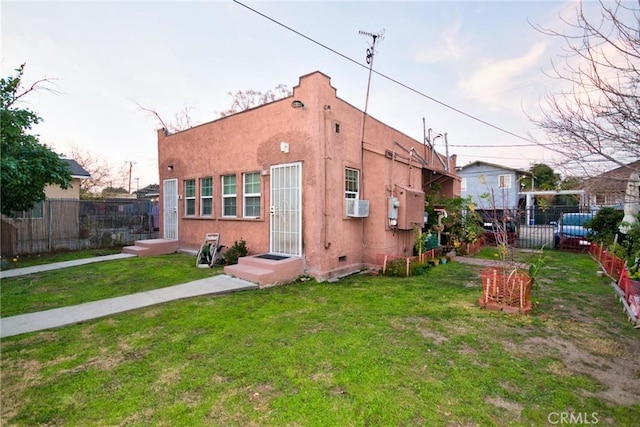 view of front of property featuring entry steps, fence, a front lawn, and stucco siding