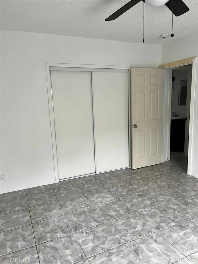 unfurnished bedroom featuring a closet, ceiling fan, and a textured ceiling