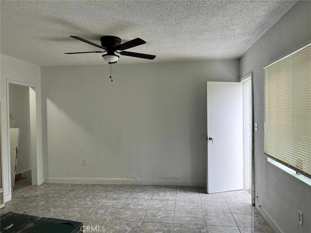 tiled spare room with a textured ceiling and a ceiling fan