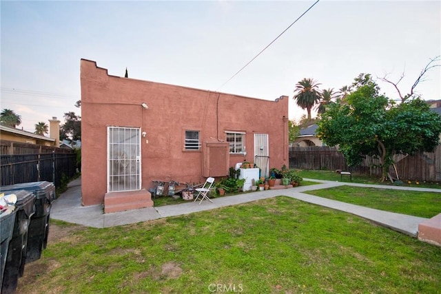 back of house featuring stucco siding, fence, and a yard