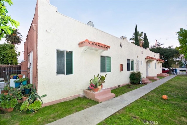 view of side of home with a yard, fence, and stucco siding