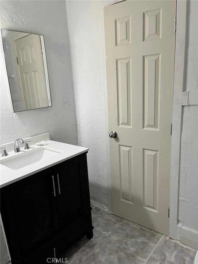 bathroom with a textured wall and vanity