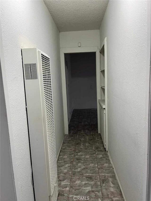 hall with tile patterned flooring, a heating unit, and a textured ceiling