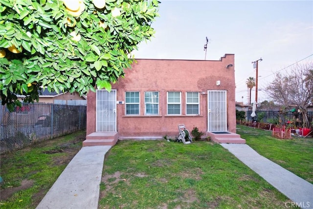 bungalow featuring a front yard, fence, and stucco siding