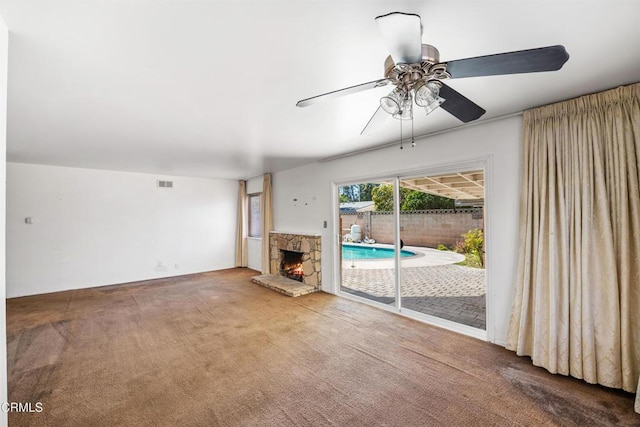 unfurnished living room featuring carpet floors, a fireplace, visible vents, and a ceiling fan