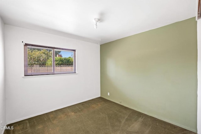 empty room with dark carpet and baseboards