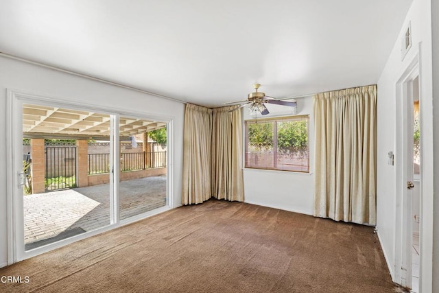 carpeted empty room featuring ceiling fan and a wealth of natural light