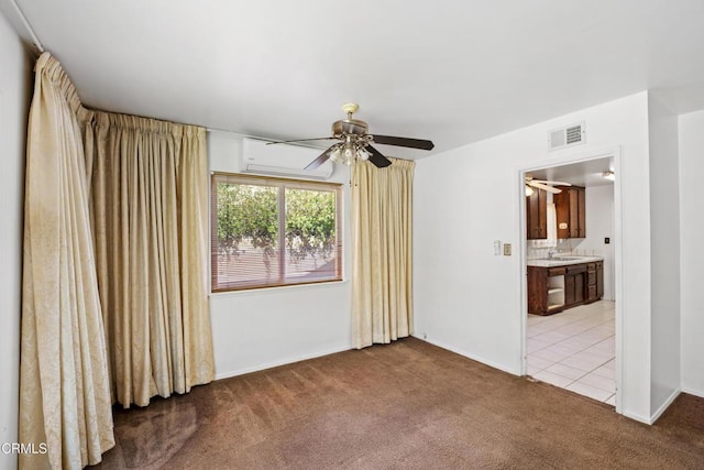 spare room featuring carpet, visible vents, a ceiling fan, an AC wall unit, and a sink