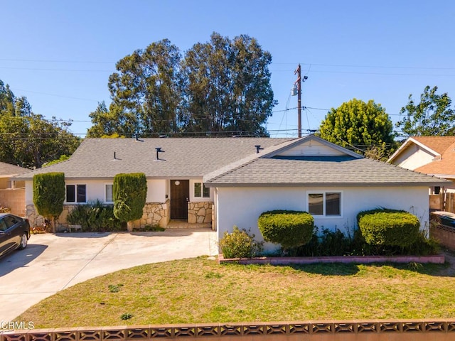 single story home featuring driveway, a shingled roof, stone siding, a front lawn, and stucco siding