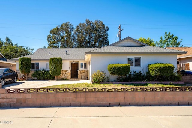 single story home featuring stone siding, a fenced front yard, and stucco siding