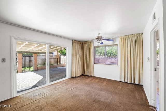 carpeted empty room with a healthy amount of sunlight, visible vents, and a ceiling fan