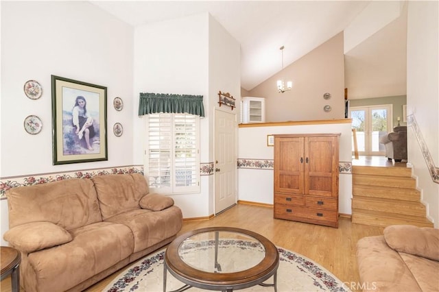 living room with vaulted ceiling, a chandelier, and light wood-style floors