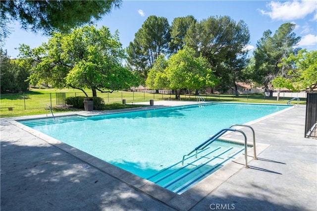 community pool featuring a patio area, fence, and a lawn