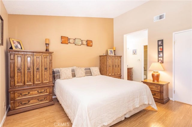 bedroom featuring light wood-type flooring, visible vents, lofted ceiling, and baseboards