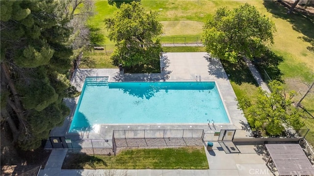 view of swimming pool featuring fence and a lawn