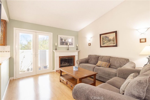 living area with light wood-style floors, lofted ceiling, a fireplace, and baseboards