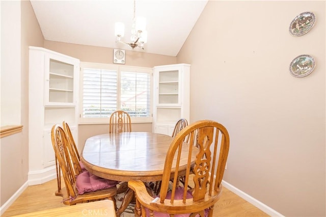 dining room with lofted ceiling, light wood finished floors, a chandelier, and baseboards