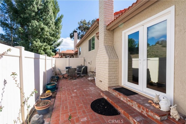 view of patio / terrace featuring a fenced backyard, central AC unit, and french doors