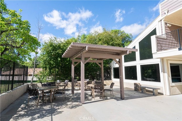 view of patio / terrace with a balcony, fence, a pergola, and outdoor dining space