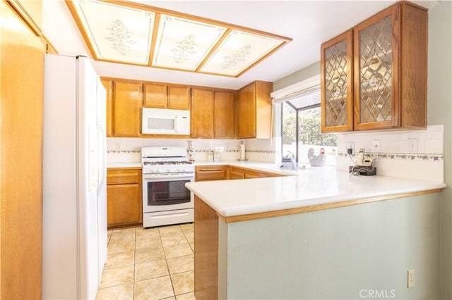 kitchen featuring white appliances, light tile patterned flooring, a peninsula, and decorative backsplash