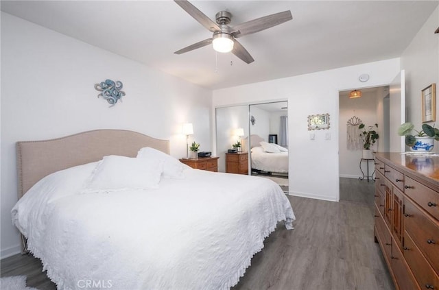 bedroom featuring a ceiling fan, a closet, dark wood finished floors, and baseboards