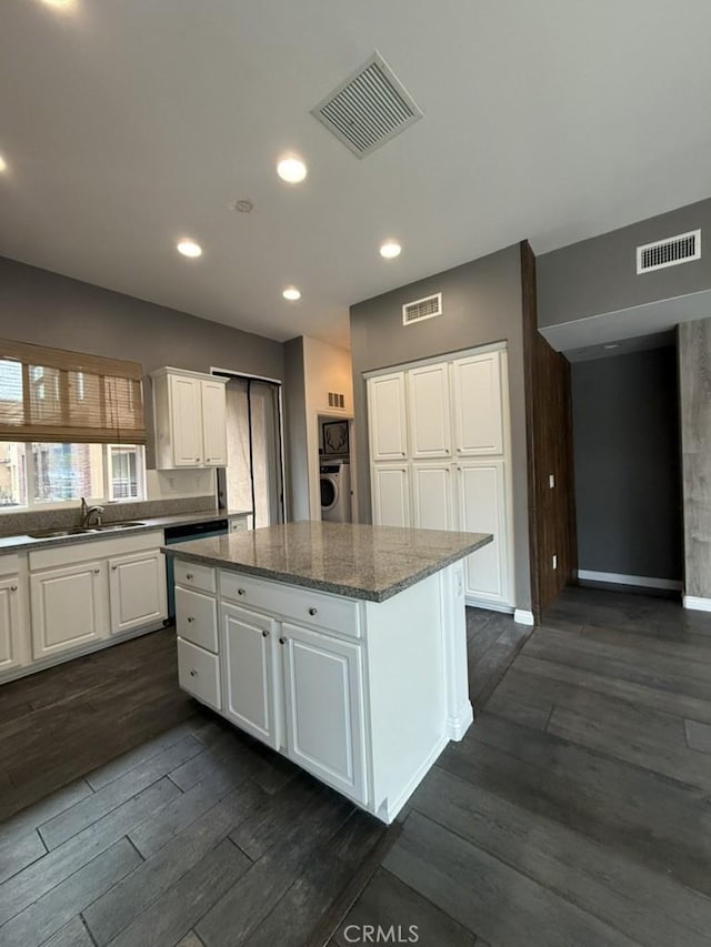 kitchen with a center island, a sink, visible vents, and white cabinetry