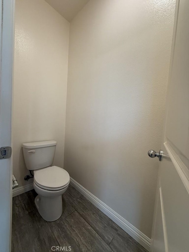 bathroom with baseboards, toilet, and wood finished floors