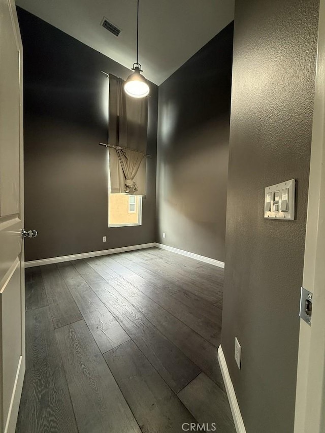 unfurnished room with baseboards, visible vents, and hardwood / wood-style floors