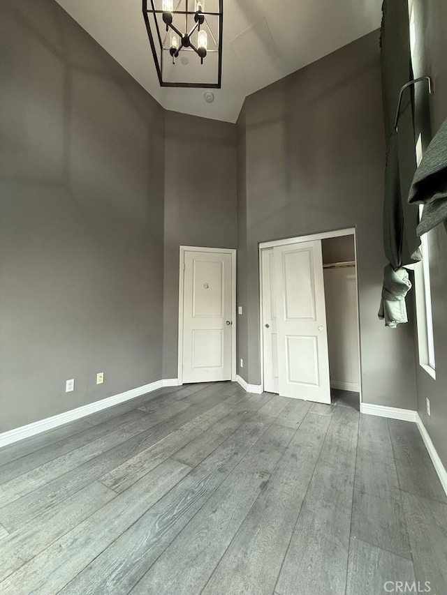 foyer featuring a high ceiling, baseboards, a chandelier, and wood finished floors