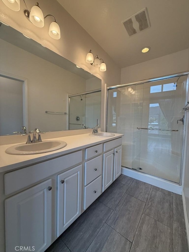 bathroom featuring a stall shower, visible vents, a sink, and double vanity