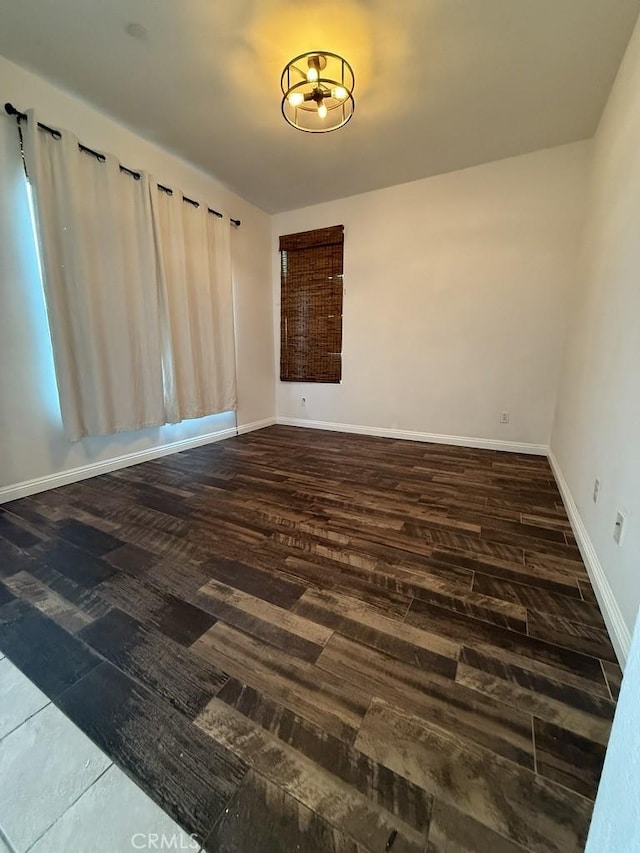 spare room with baseboards and wood finished floors