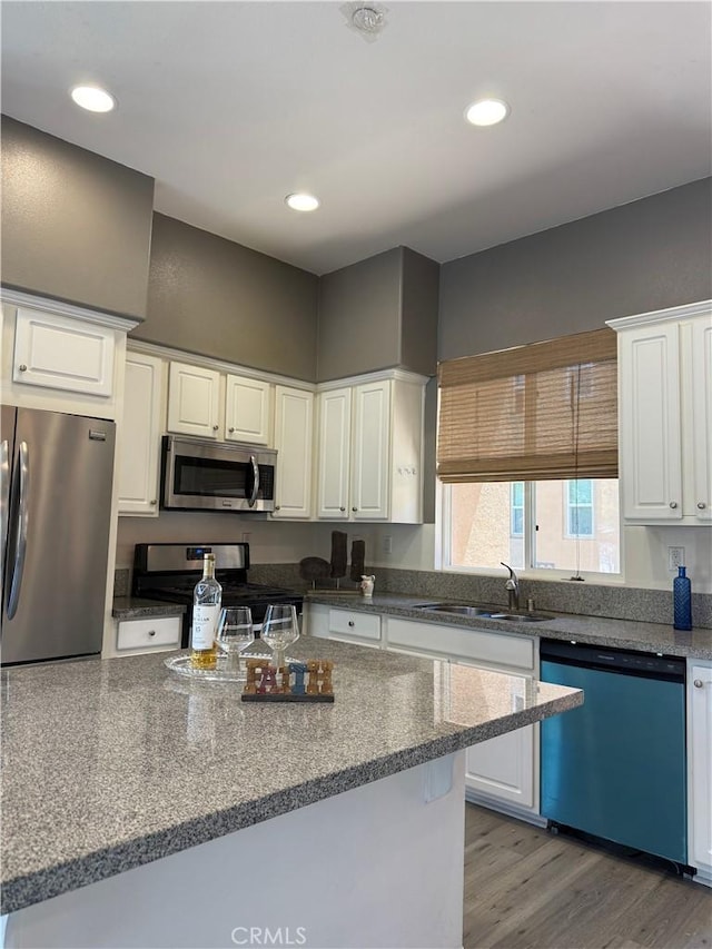 kitchen featuring stainless steel appliances, light wood-style flooring, a sink, and white cabinetry