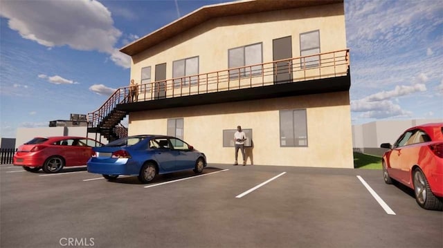 view of property with uncovered parking and stairway