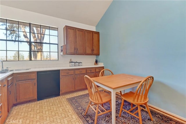 kitchen with black dishwasher, light countertops, brown cabinetry, and a sink