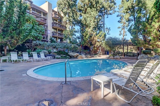 community pool with a patio area and a pergola