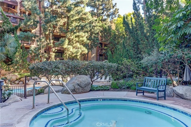 view of swimming pool featuring fence and a community hot tub