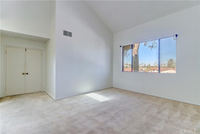 unfurnished bedroom with high vaulted ceiling, a closet, visible vents, and carpet flooring