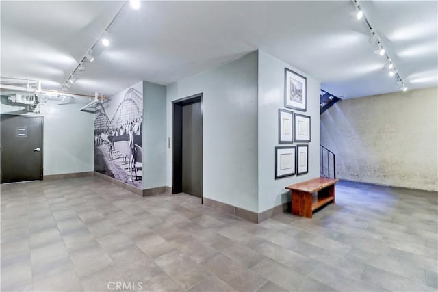 interior space with baseboards, stairway, and track lighting