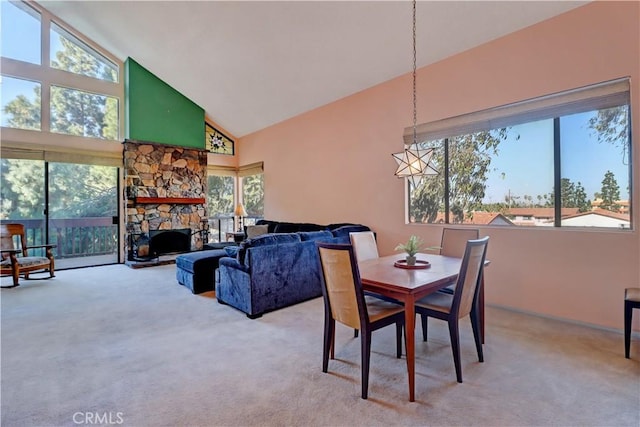 dining room with light carpet, high vaulted ceiling, and a stone fireplace