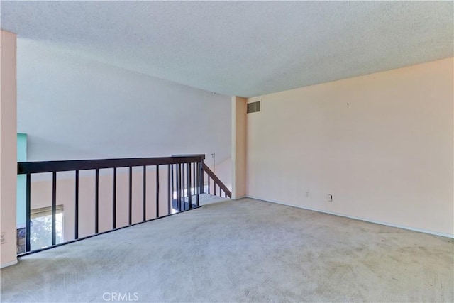 spare room with a textured ceiling, carpet, and visible vents