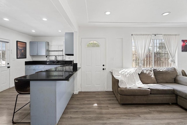 kitchen featuring a breakfast bar area, a peninsula, dark wood-style flooring, dark countertops, and open floor plan