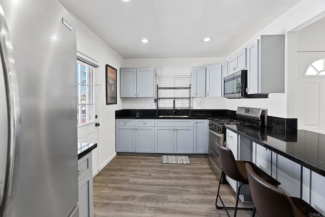 kitchen with a breakfast bar, recessed lighting, appliances with stainless steel finishes, light wood-style floors, and a sink